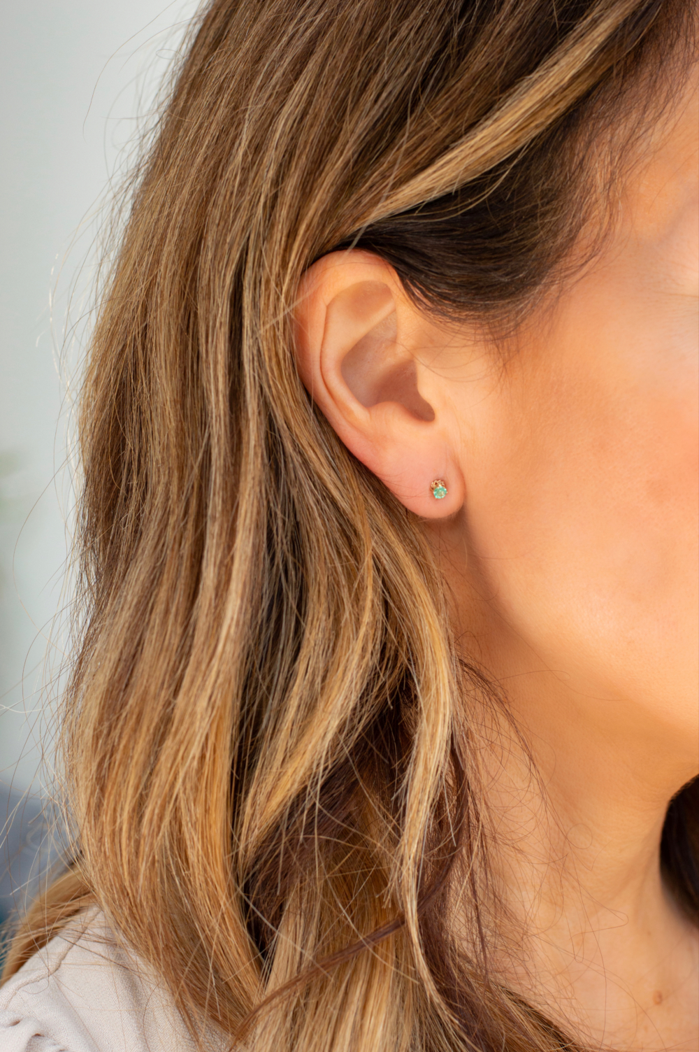 small 9ct gold and emerald stud earrings in woman's ear