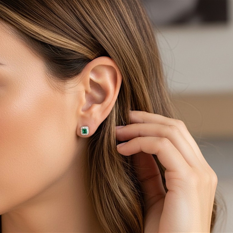 art deco style emerald and diamond studs in white gold for sale in Leeds shown in a model's ear