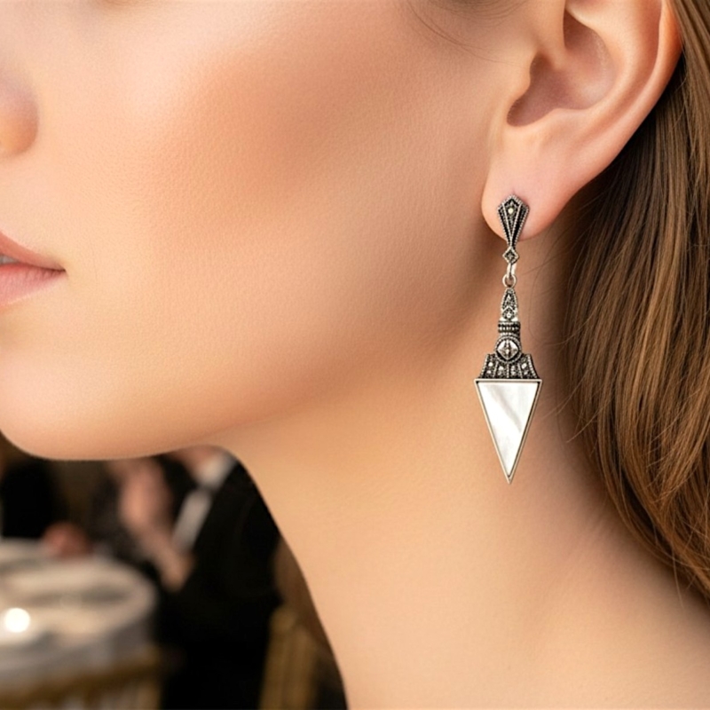 art deco style mother of pearl earrings in silver with marcasite stones, shown on a model