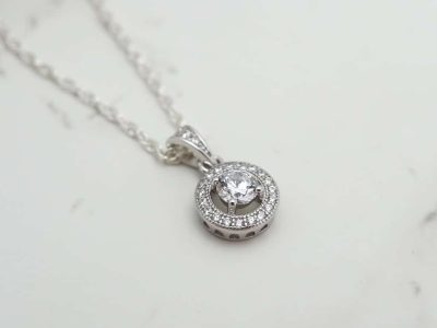 silver and CZ halo pendant on a chain flat lay