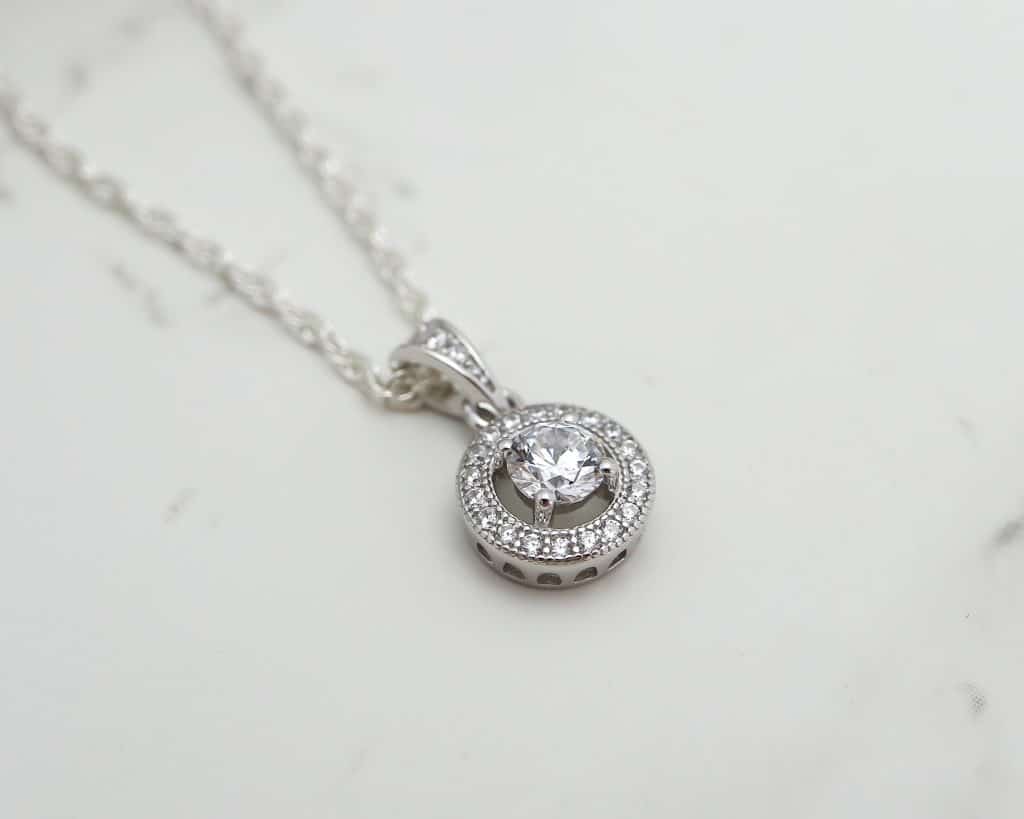 silver and CZ halo pendant on a chain flat lay