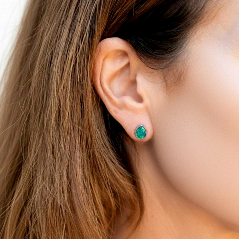 modern silver opal pear shaped stud earrings for pierced ears in dark blue/green in model ear