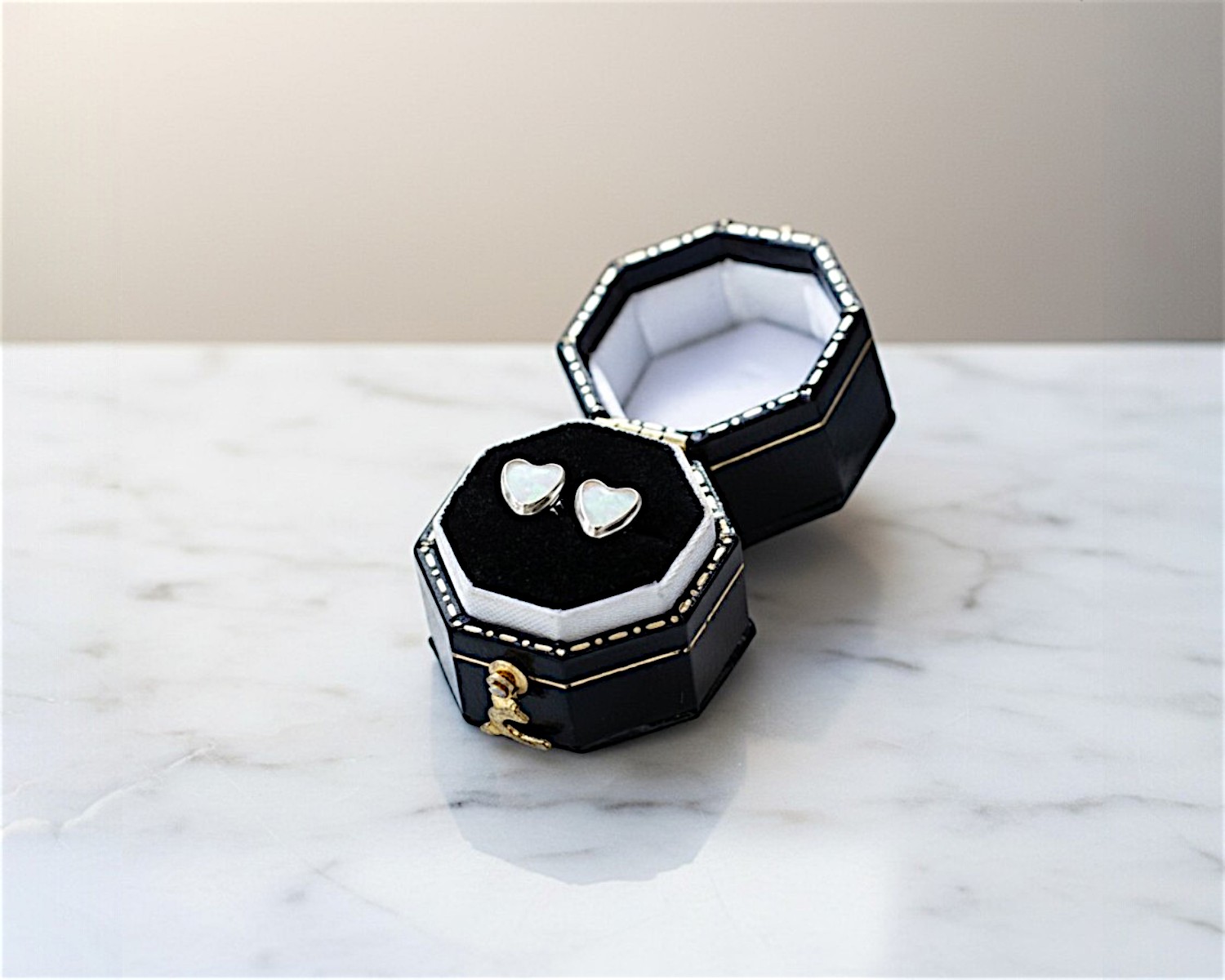 white opal heart studs in silver in a black box