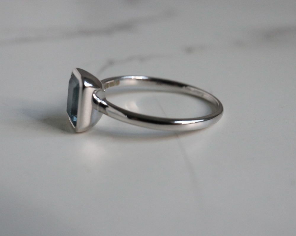 9ct white gold and blue topaz emerald cut ring in a bezel setting