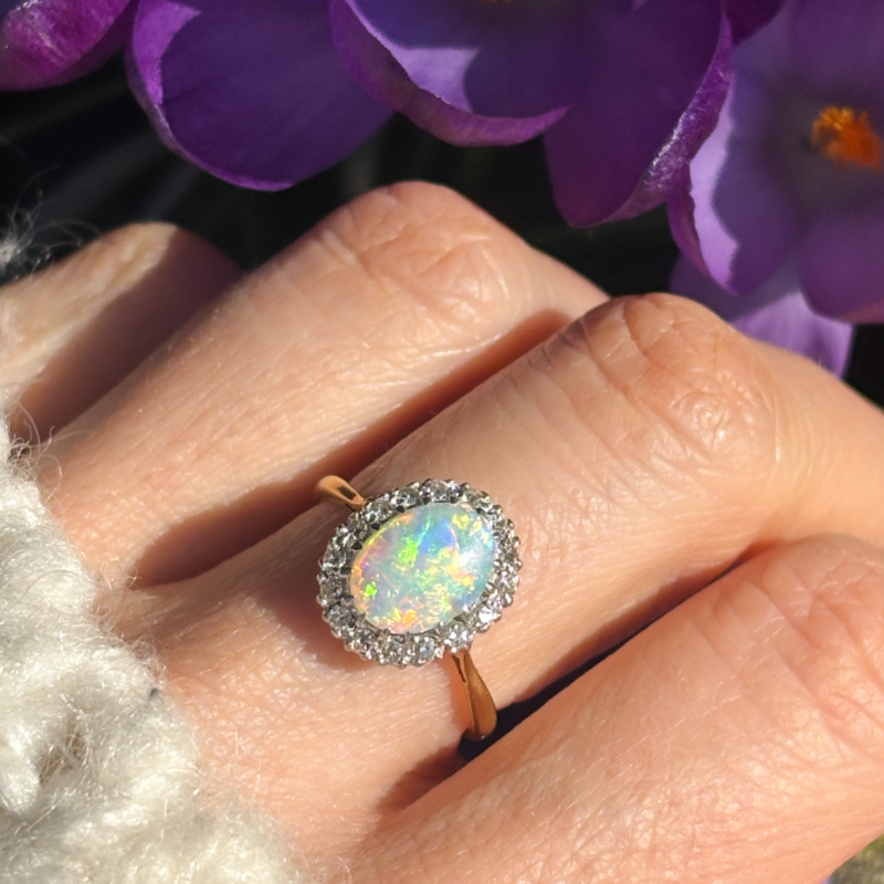 antique 1930s opal and diamond cluster ring for sale in Leeds, UK on hand next to purple flowers