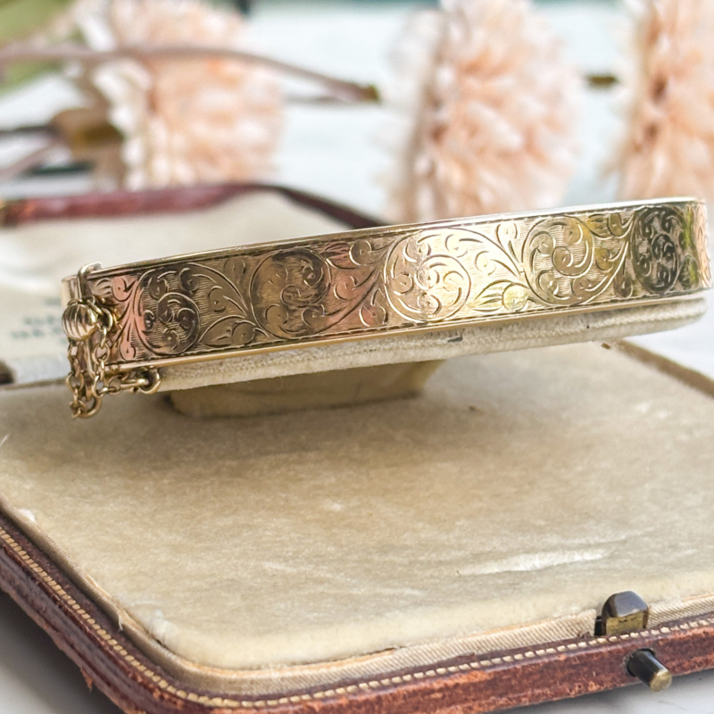 vintage 9ct gold bangle with metal core engraved floral pattern on one side, shown in presentation box