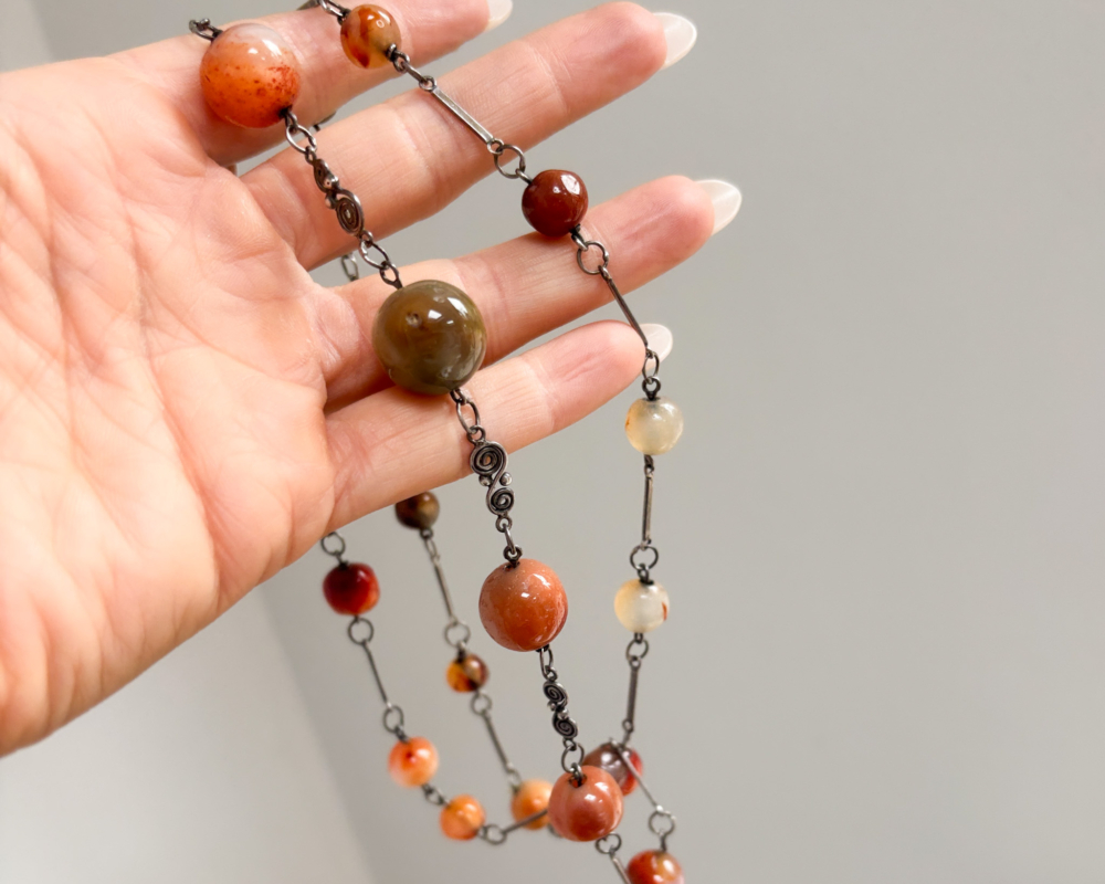 antique 1920s agate beads for sale, held up against a lady's hand
