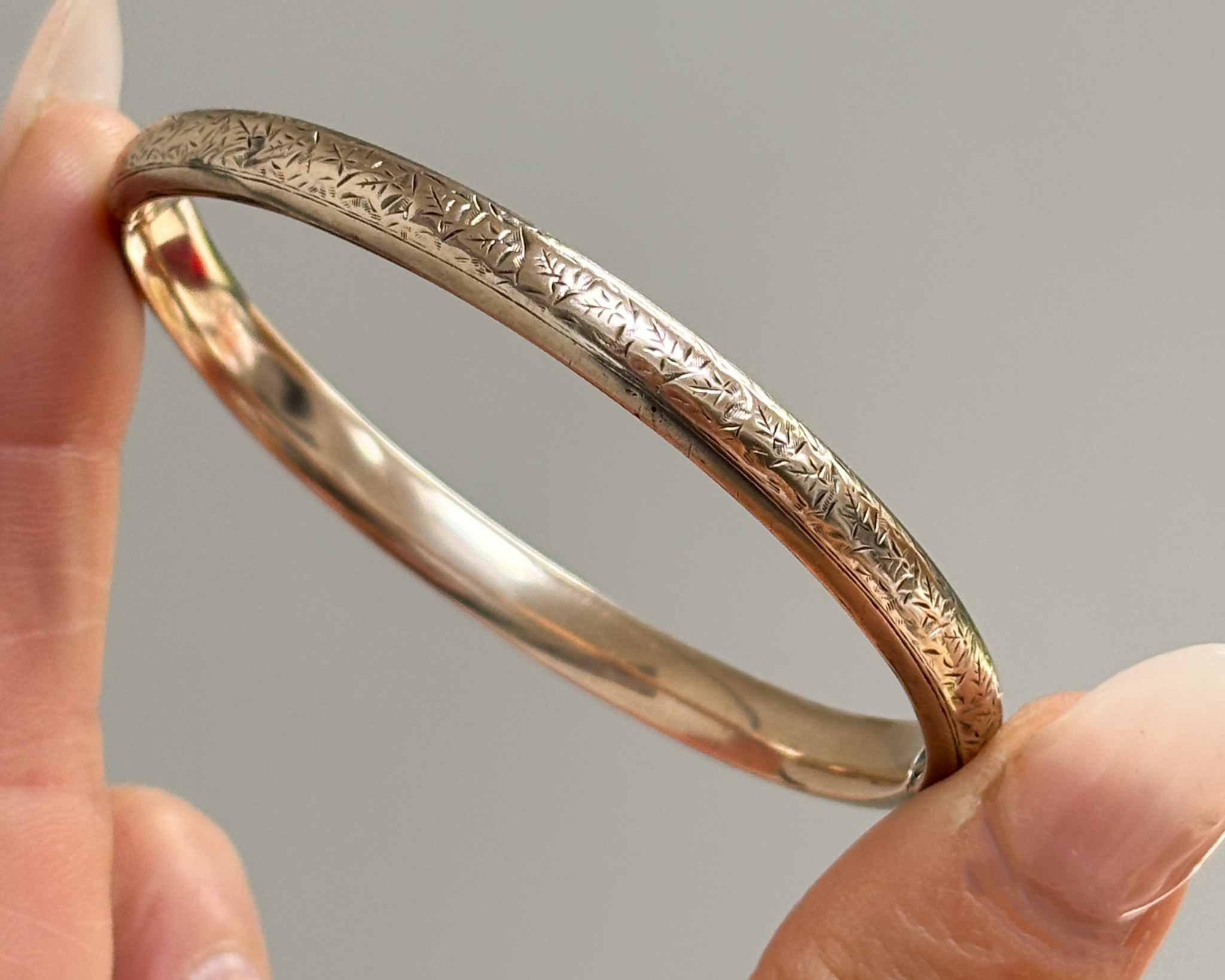 antique Edwardian 9ct gold engraved bangle for sale in Leeds, UK. Shown between lady's fingers