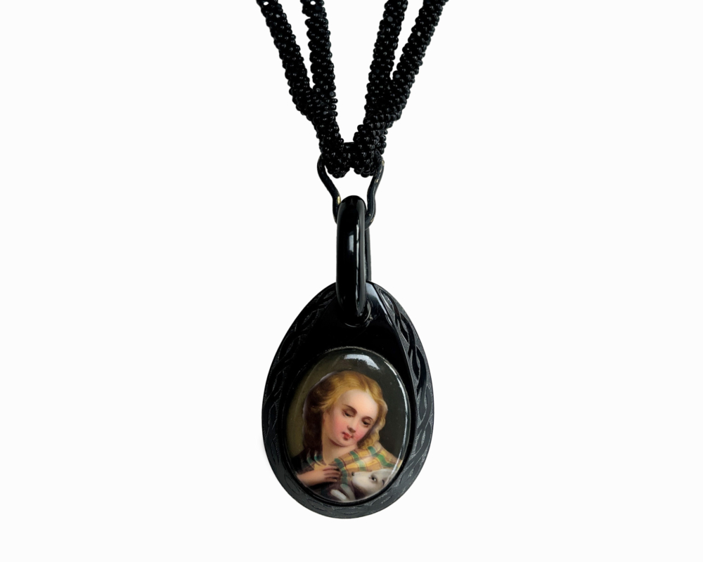 antique Victorian Whitby Jet beads with pendant hanging from them showing the image of a person in Victorian times