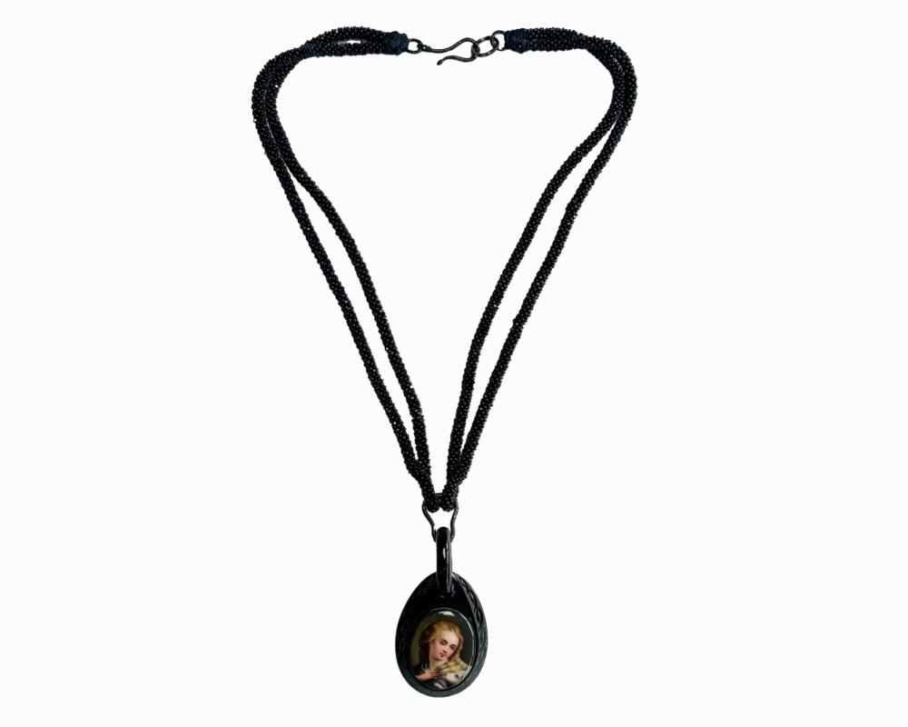 antique Victorian Whitby Jet beads with pendant hanging from them showing the image of a person in Victorian times