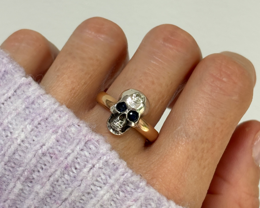 antique Victorian 9ct gold skull ring with diamond and sapphire for sale in Leeds, shown on lady's finger