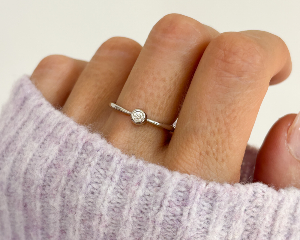 modern 9ct white gold bezel set diamond ring shown on a lady's finger