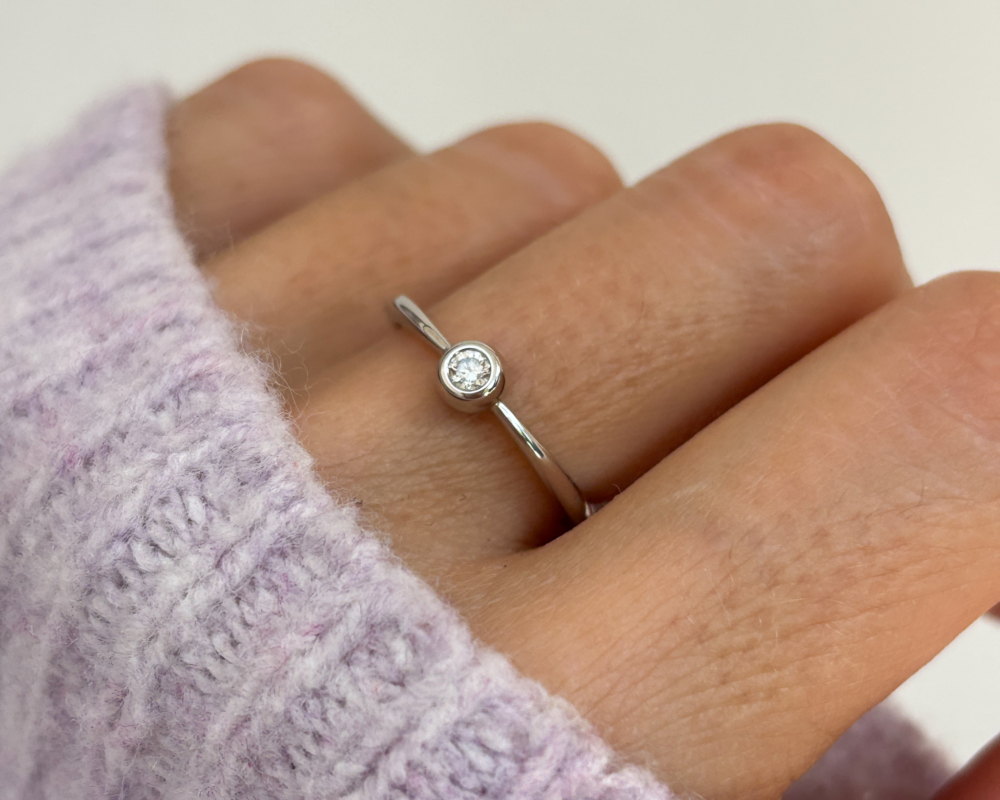 modern 9ct white gold bezel set diamond ring shown on a lady's finger