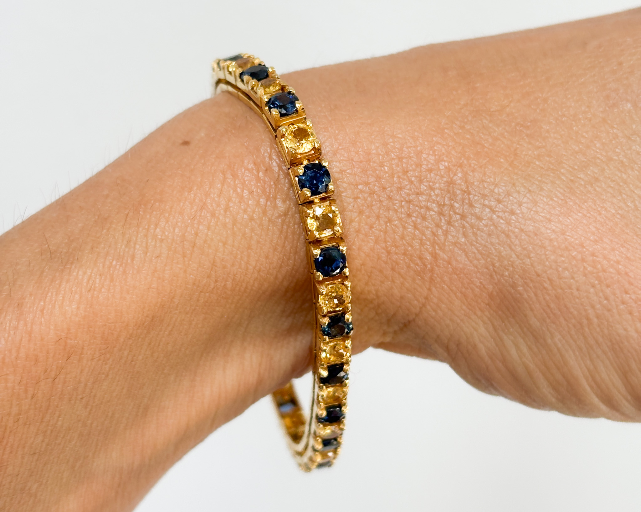 pre-owned blue sapphire and yellow sapphire tennis bracelet in 14ct gold for sale in Leeds, shown on a woman's wrist
