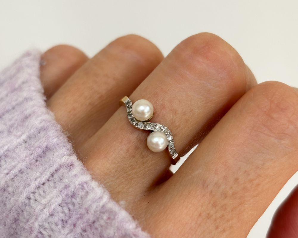 antique Edwardian pearl toi et moi ring set with diamonds, shown on a woman's finger