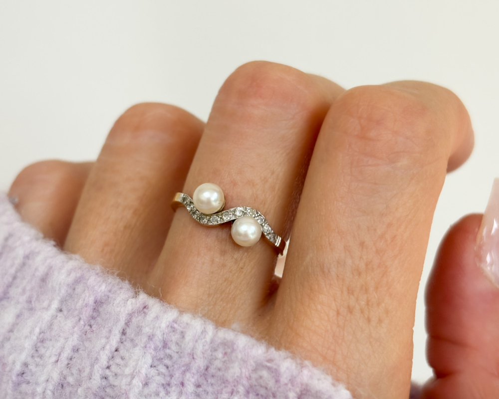 antique Edwardian pearl toi et moi ring set with diamonds, shown on a woman's finger