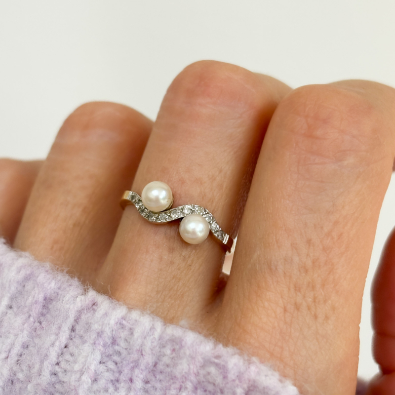 antique Edwardian pearl toi et moi ring set with diamonds, shown on a woman's finger