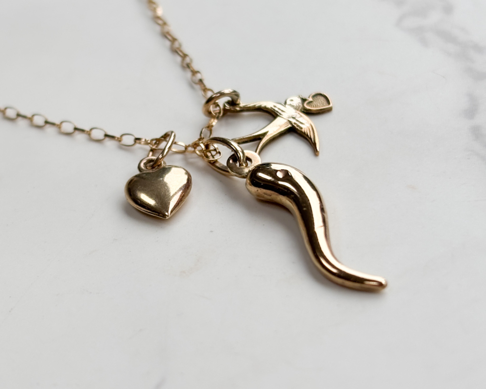 vintage 9ct gold charm necklace with heart charm, horn of plenty and bird on a gold chain.