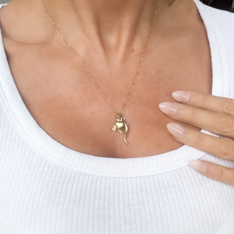 vintage 9ct gold charm necklace with heart charm, horn of plenty and bird on a gold chain. Shown on woman's neck