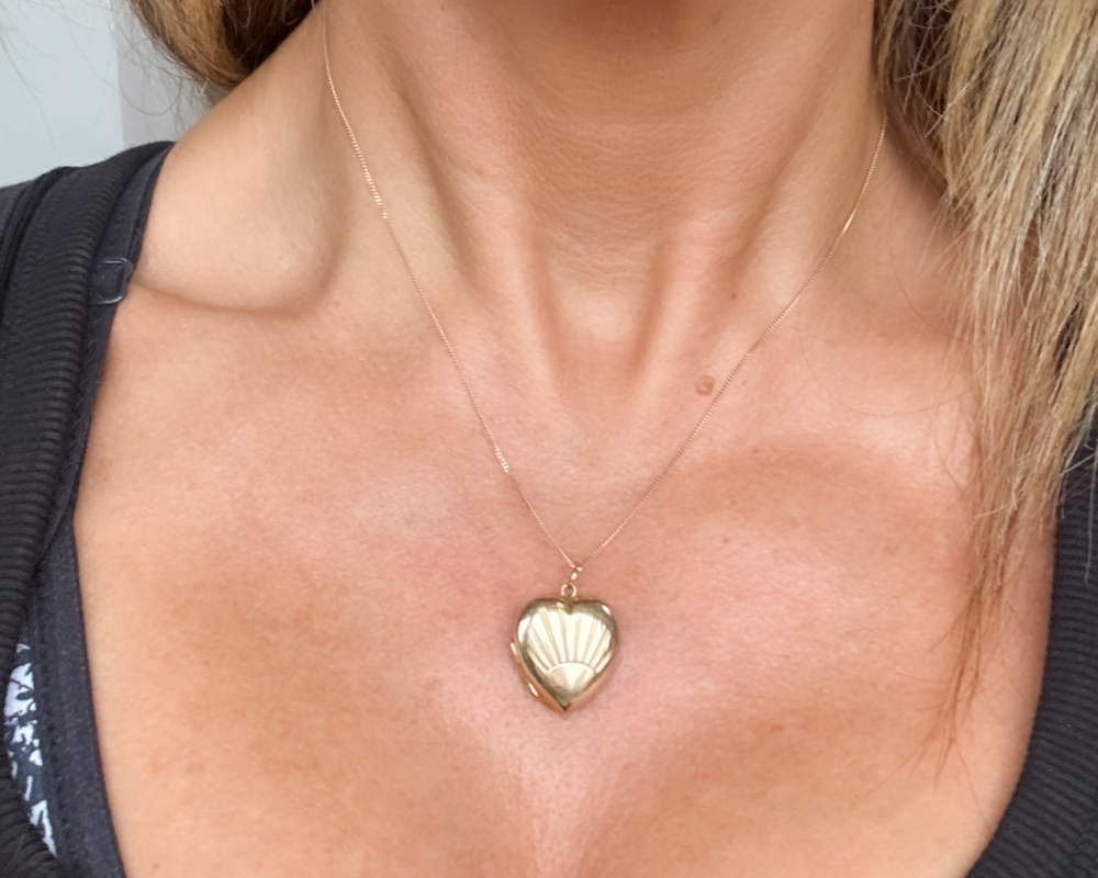 vintage gold sunburst heart locket and chain for sale in Leeds, shown on a woman's neck
