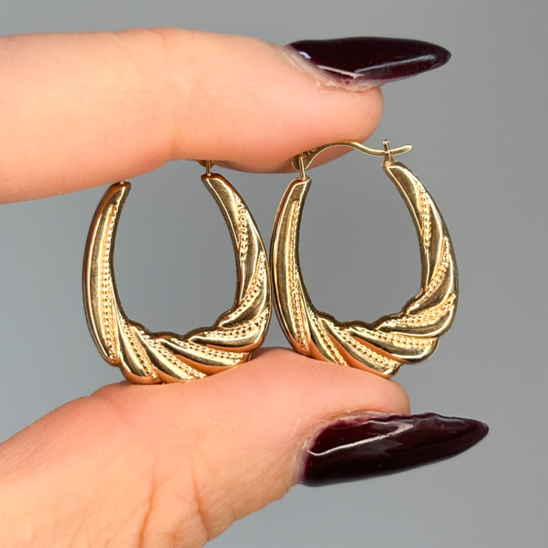 vintage textured gold hoop earrings held in woman's hand