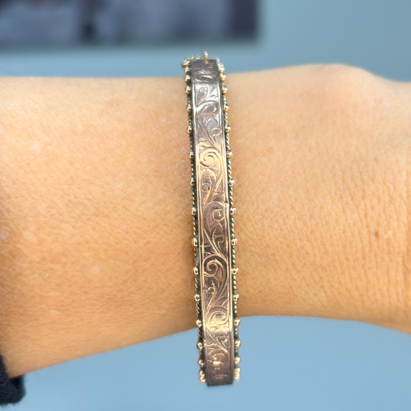 antique Victorian rose gold bangle with engraving and safety chain for sale in Leeds, shown on woman's hand