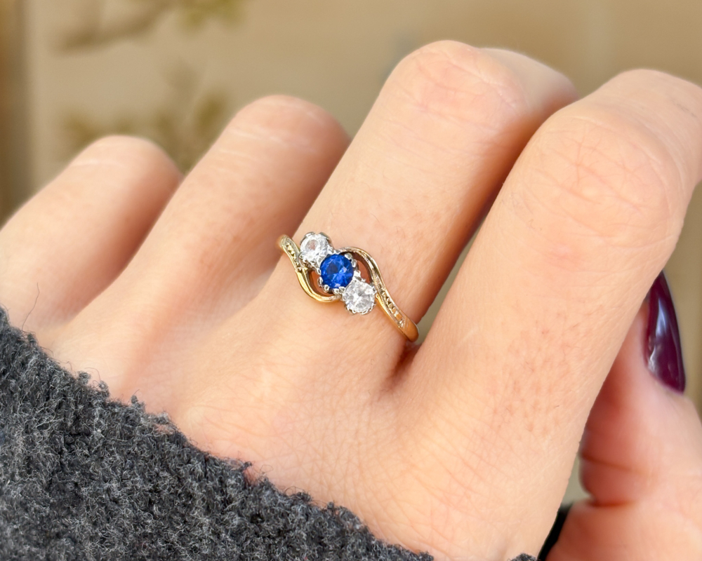 antique bypass ring with blue and white stones in 18ct gold for sale in Leeds, shown on woman's hand