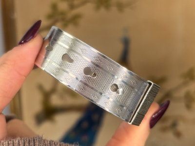antique Charles Horner silver buckle bangle, held in woman's fingers