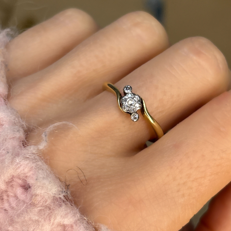 antique 1920s diamond daisy cluster ring in 18ct yellow gold with bypass setting, shown on woman's hand