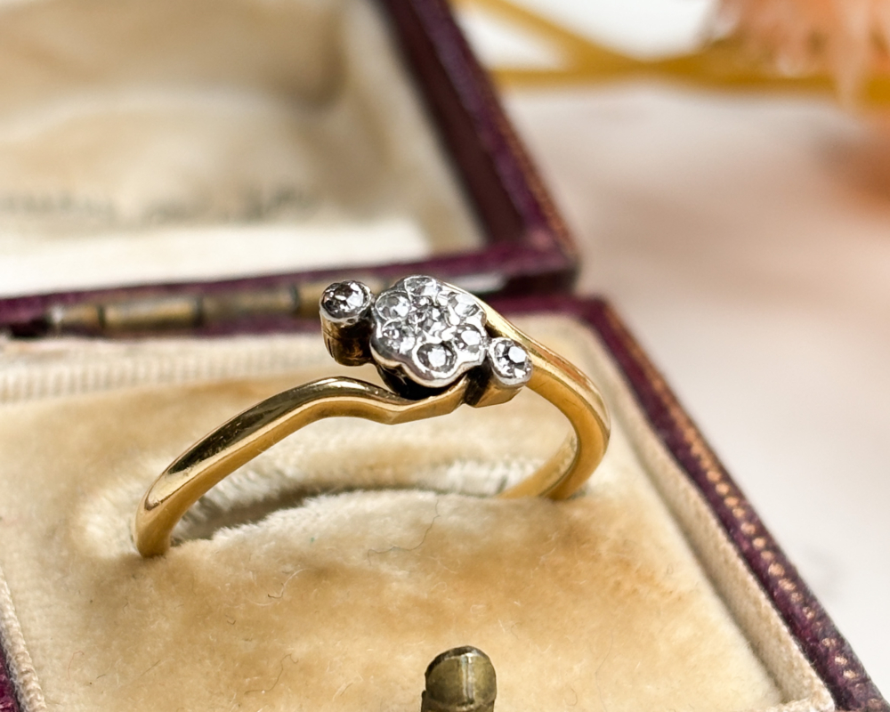 antique 1920s diamond daisy cluster ring in 18ct yellow gold with bypass setting, shown in antique brown box