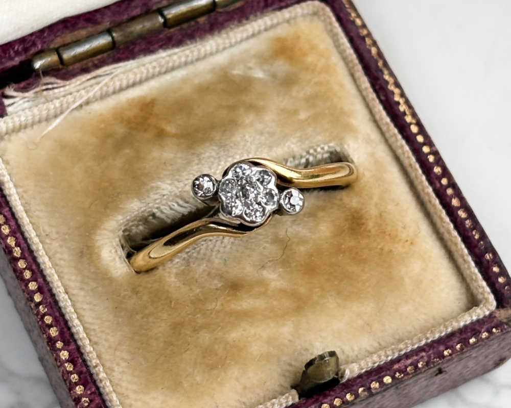 antique 1920s diamond daisy cluster ring in 18ct yellow gold with bypass setting, shown in brown box