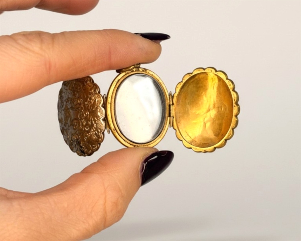 antique Edwardian fanily locket made from pinchbeck with scrolled chased detail, open to show compartments