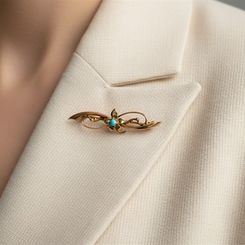antique turquoise brooch in 9ct gold dated 1900 shown on a model's blazer lapel