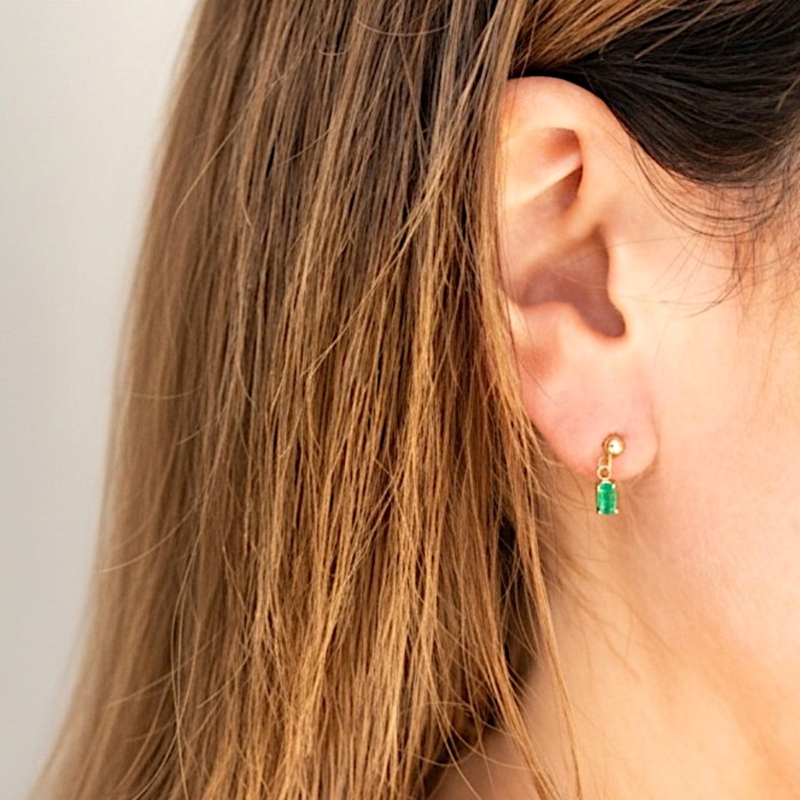 modern emerald drop earrings in 9ct gold for sale in Leeds, UK in model's ear
