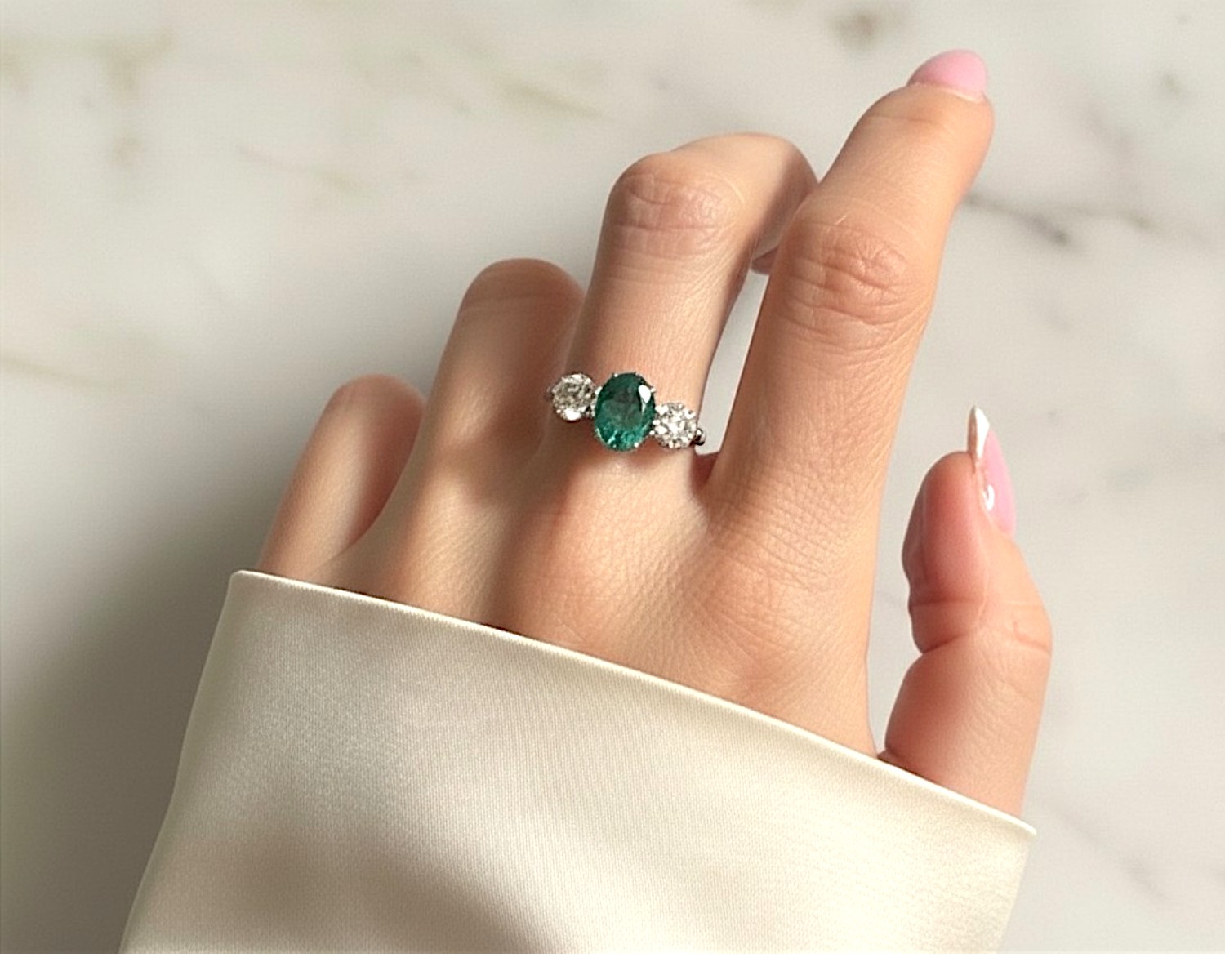emerald three stone ring on hand