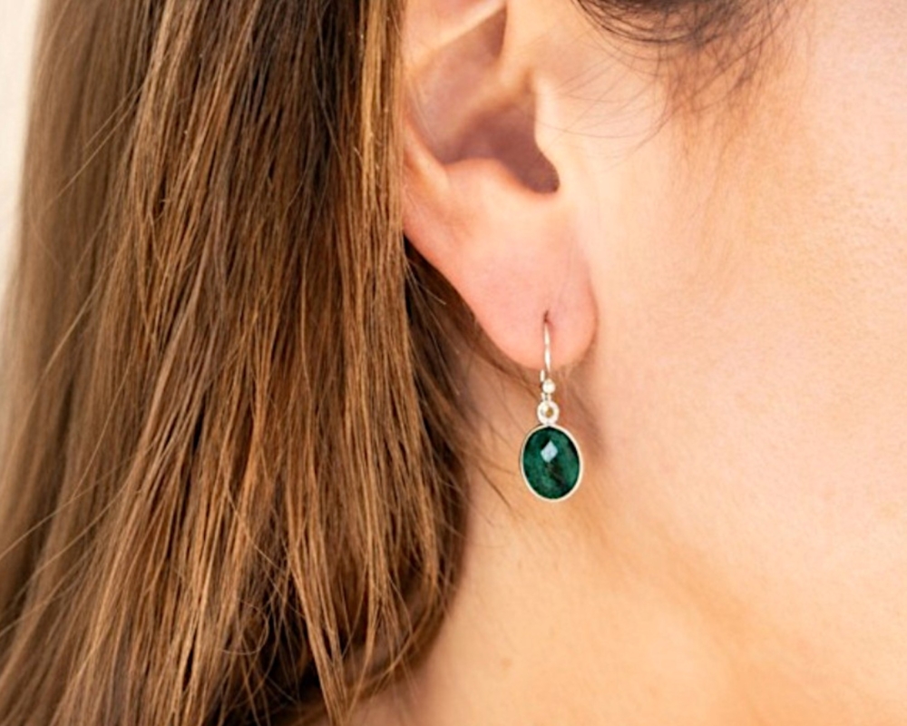 silver and emerald oval drop earrings with ear wire for sale in Leeds, UK, shown in model's ear