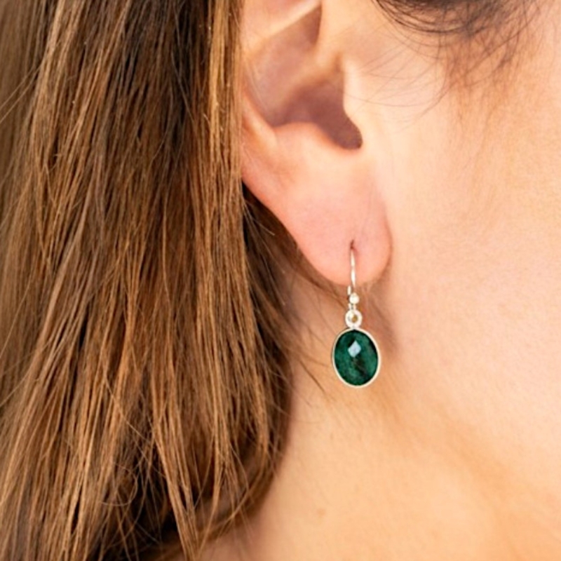 silver and emerald oval drop earrings with ear wire for sale in Leeds, UK, shown in model's ear