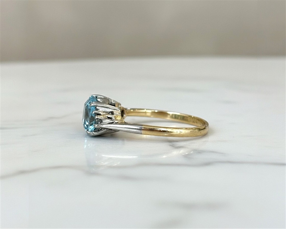 Art Deco aquamarine and diamond ring set with an emerald cut aquamarine and two round diamonds in 18ct yellow gold and platinum. For sale in Leeds, UK, showing side view of the ring