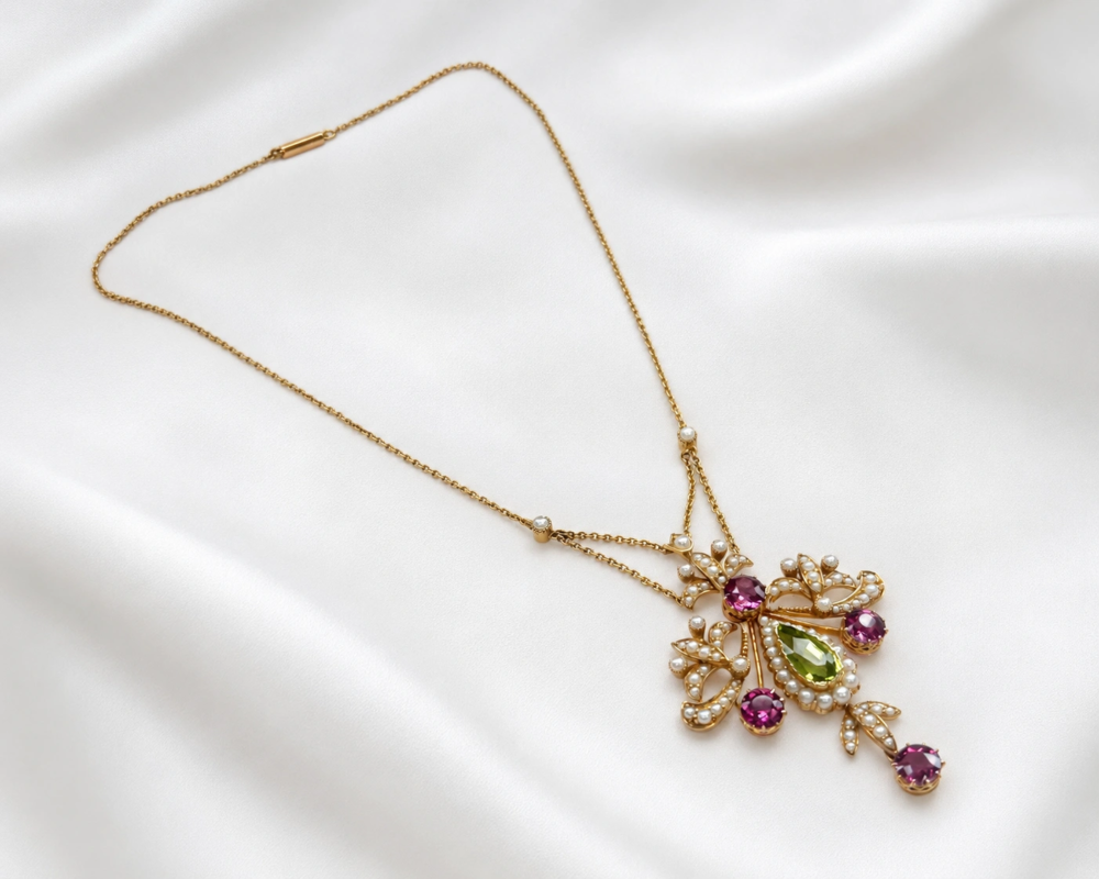 antique Edwardian suffragette necklace in 15ct gold with peridot, amethyst and seed pearl in its orginal box for sale in Leeds. Shown laying flat on white silk