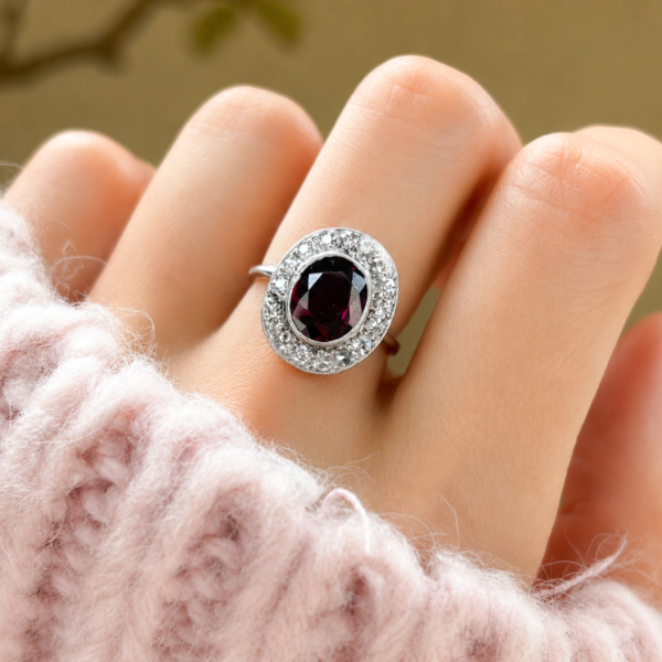 Art Deco garnet and diamond cluster ring in 18ct white gold and platinum for sale in Leeds, UK, shown on a model's hand