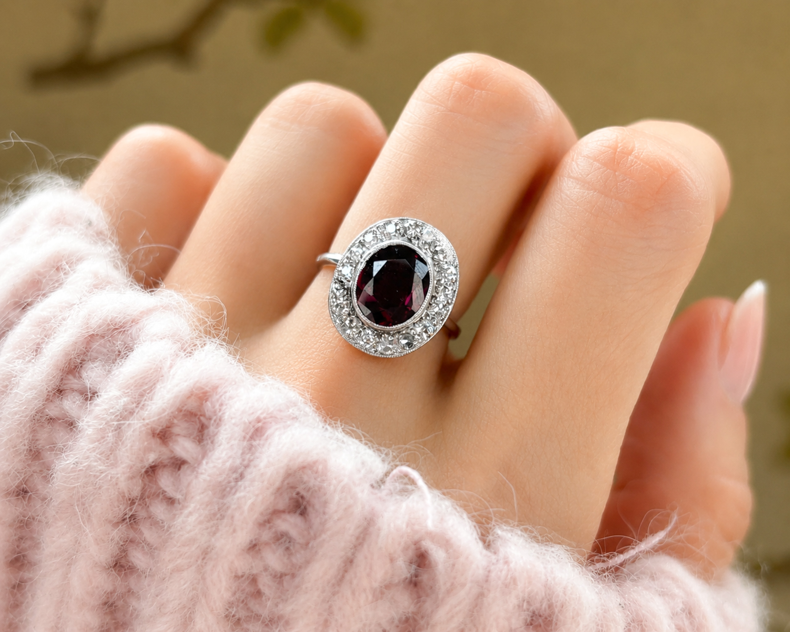 Art Deco garnet and diamond cluster ring in 18ct white gold and platinum for sale in Leeds, UK, shown on a model's hand