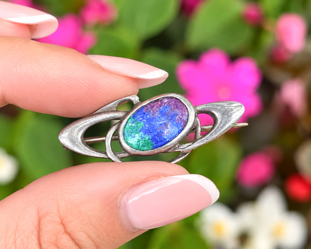 antique Charles Horner silver and enamel brooch for sale in Leeds held inbetween two fingers
