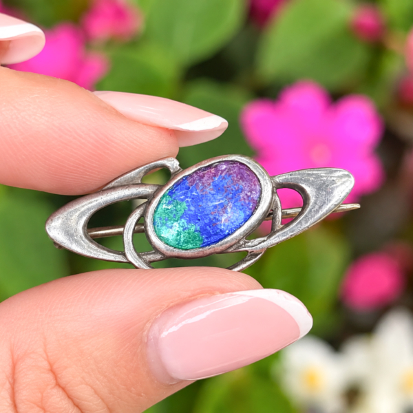 antique Charles Horner silver and enamel brooch for sale in Leeds held inbetween two fingers