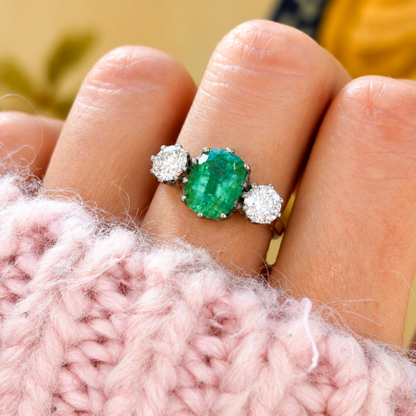 Vintage style emerald and diamond three stone ring in platinum for sale in Leeds on a finger