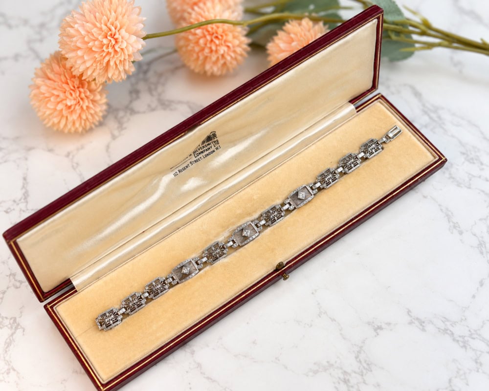 Art Deco 14ct white gold diamond panel bracelet with rock crystal panels and filigree detail, for sale in Leeds. Displayed in an antique brown bracelet box