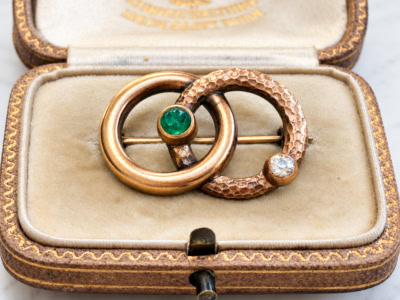 antique Victorian serpent brooch in gold with emerald and old cut diamond, displayed in an antique box