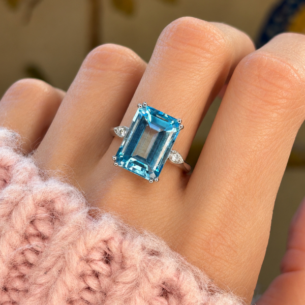 A model wearing an art deco style blue topaz and diamond ring in 9ct white gold