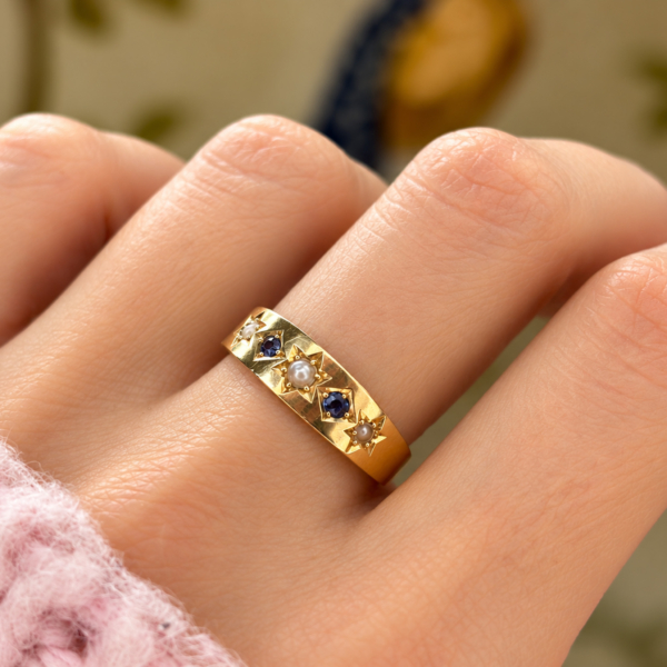 antique Edwardian era sapphire and seed pearl ring in 18ct gold and dated 1904, shown on a model's hand